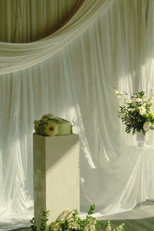 A white draped wedding ceremony with tall floral pedestals